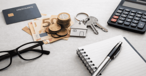 Kreditkarte, Euro-Banknoten und Münzen neben Hausschlüssel, Taschenrechner und Notizbuch als Symbol für Zinsen, Kredite und finanzielle Planung in Deutschland.